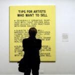 A man looks at a painting titled “Tips f